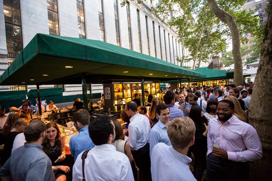 Patrons stand around the bar drinking and talking during a busy happy hour at the Bryant Park Café.