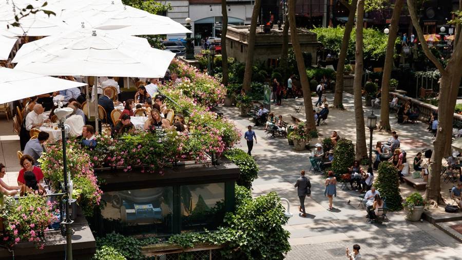 Above the ground view of the Bryant Park Grill's rooftop patio with diners, and the park in the background.