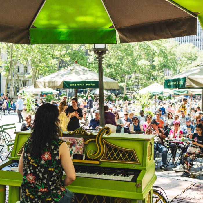 Pianist Ayako Shirasaki sits at the piano in Bryant Park NYC playing for an audience.