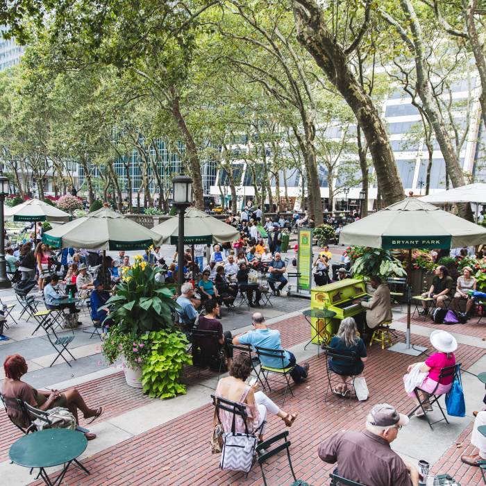 Pianist Frank Owens sits at the piano in Bryant Park NYC with a crowd of listeners.