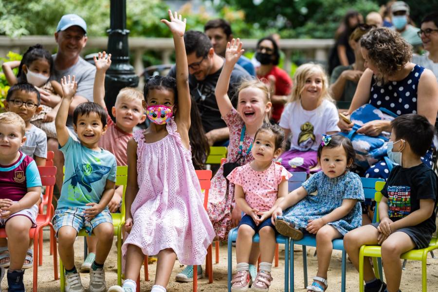 kids smiling in the audience and raising their hands