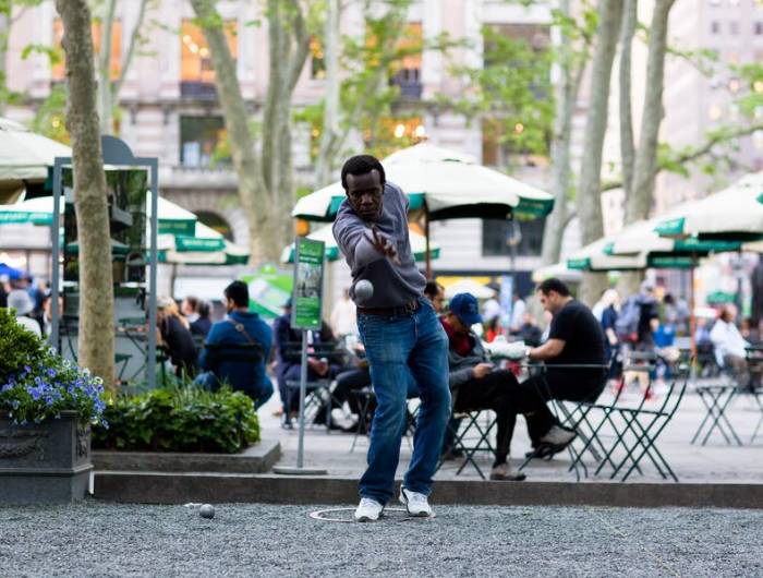 Man throws a boule on the petanque court at Bryant Park NYC.