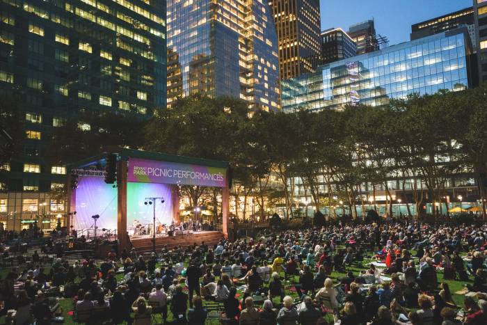 Fans sit on the lawn in front of the stage at The Town Hall Centennial Concert in Bryant Park NYC.