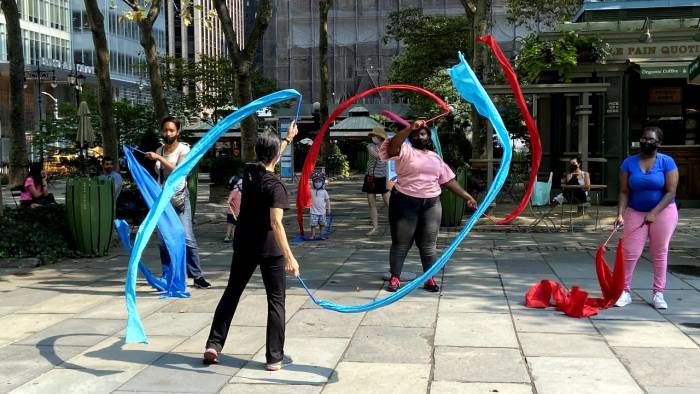 Participants dance with colorful ribbons on Bryant Park's Fountain Terrace in New York City.