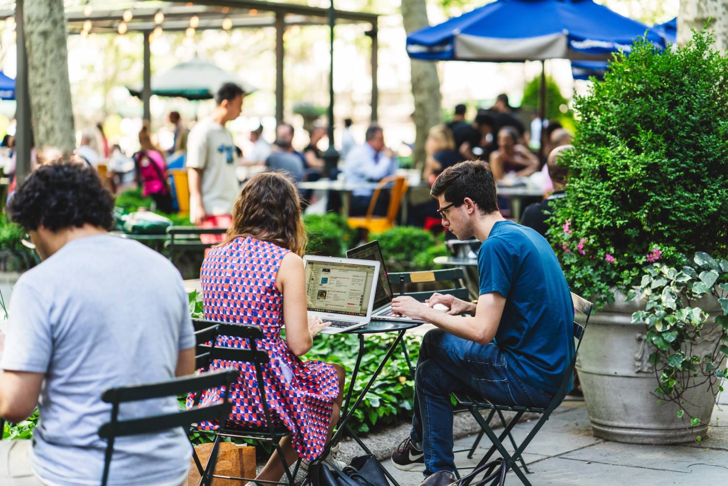 A couple sits at a table together on their laptops, using the free Bryant Park public WiFi network.