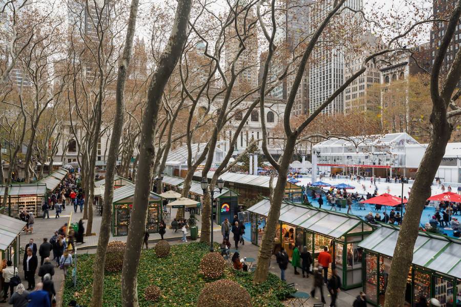 An overhead view of the Holiday Shops at Bryant Park NYC, with the rink and skaters in the background.
